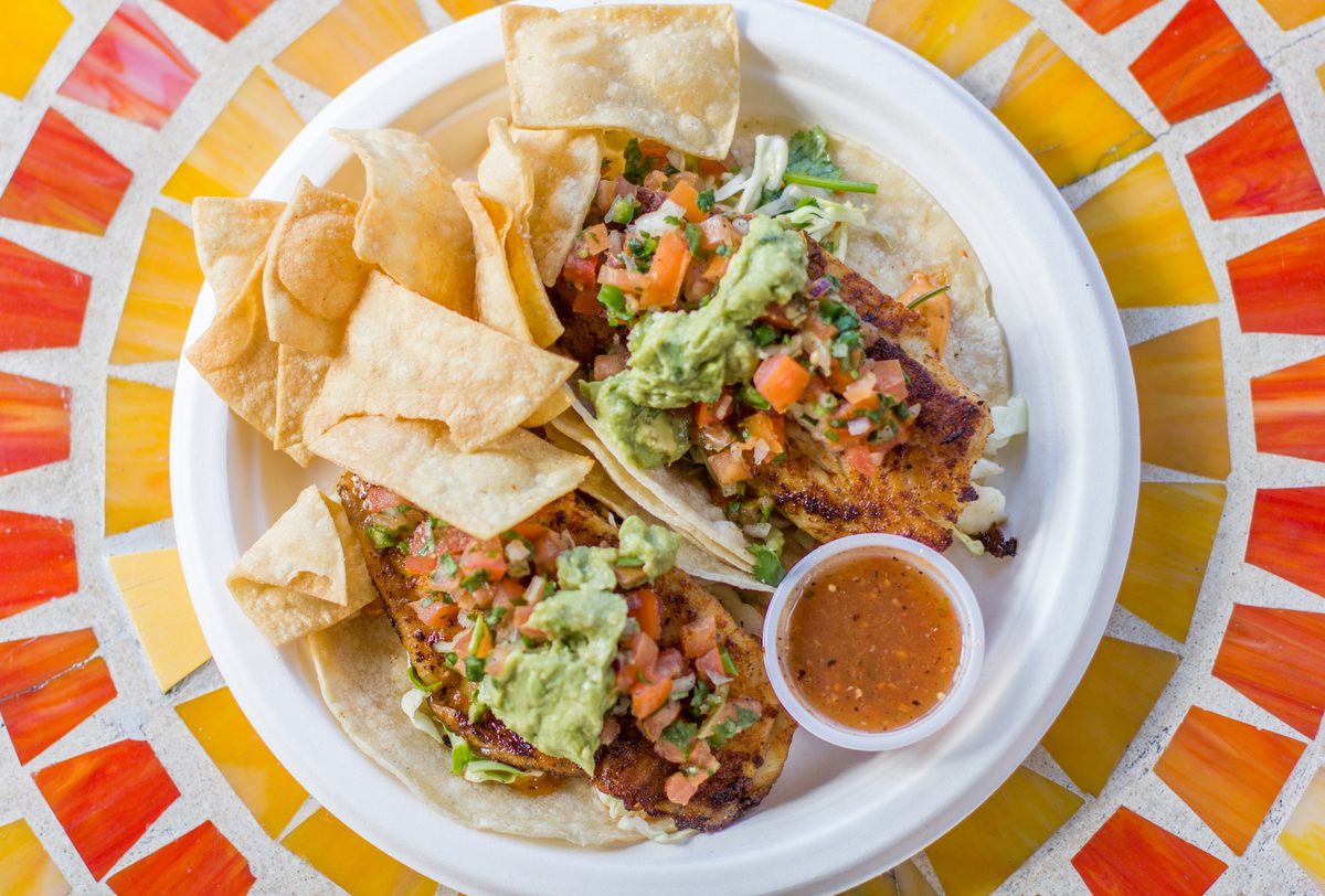 Two fish tacos with pico de gallo and guacamole