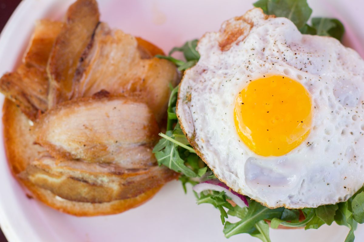Pork belly sandwich with arugula and fried egg