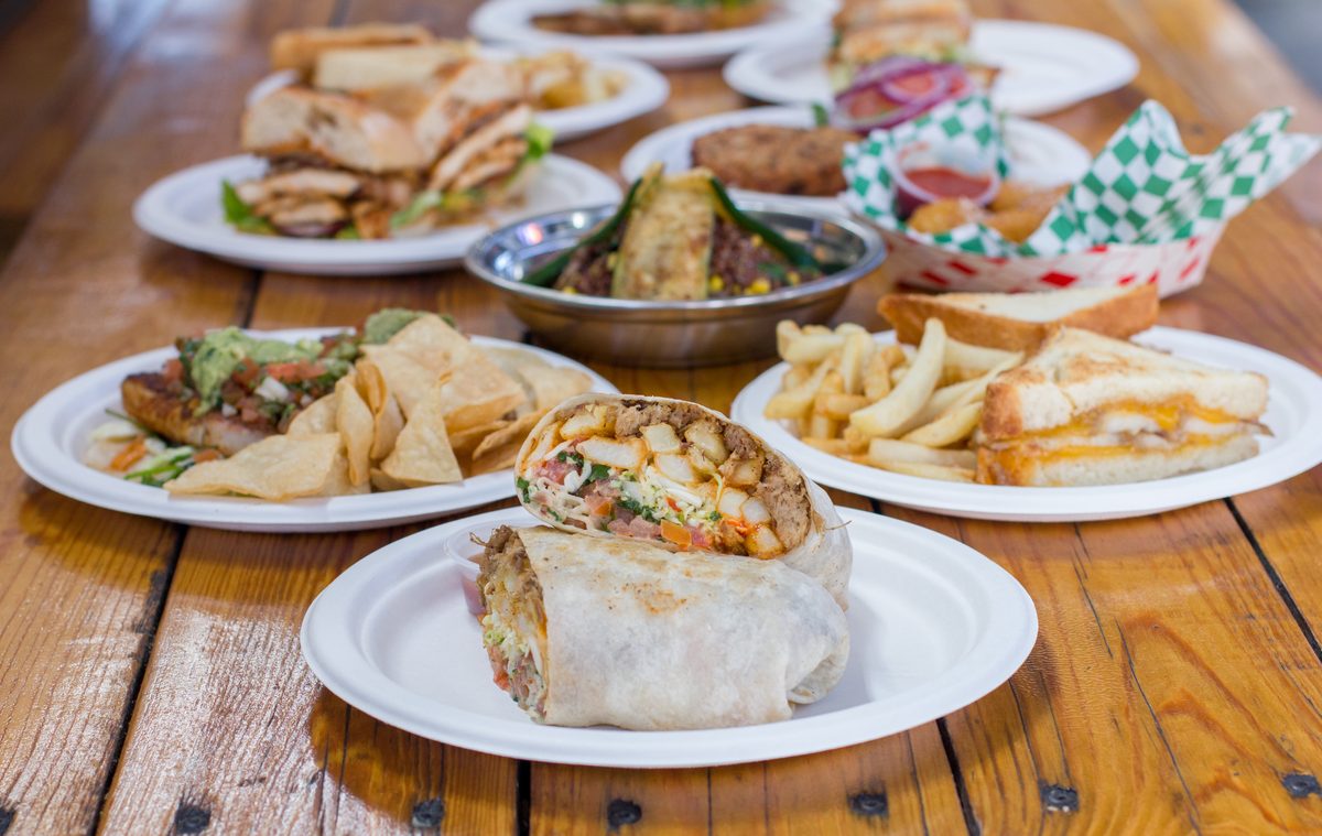 A table covered with Chef's Truck plates — burritos, sandwiches, fries and tacos